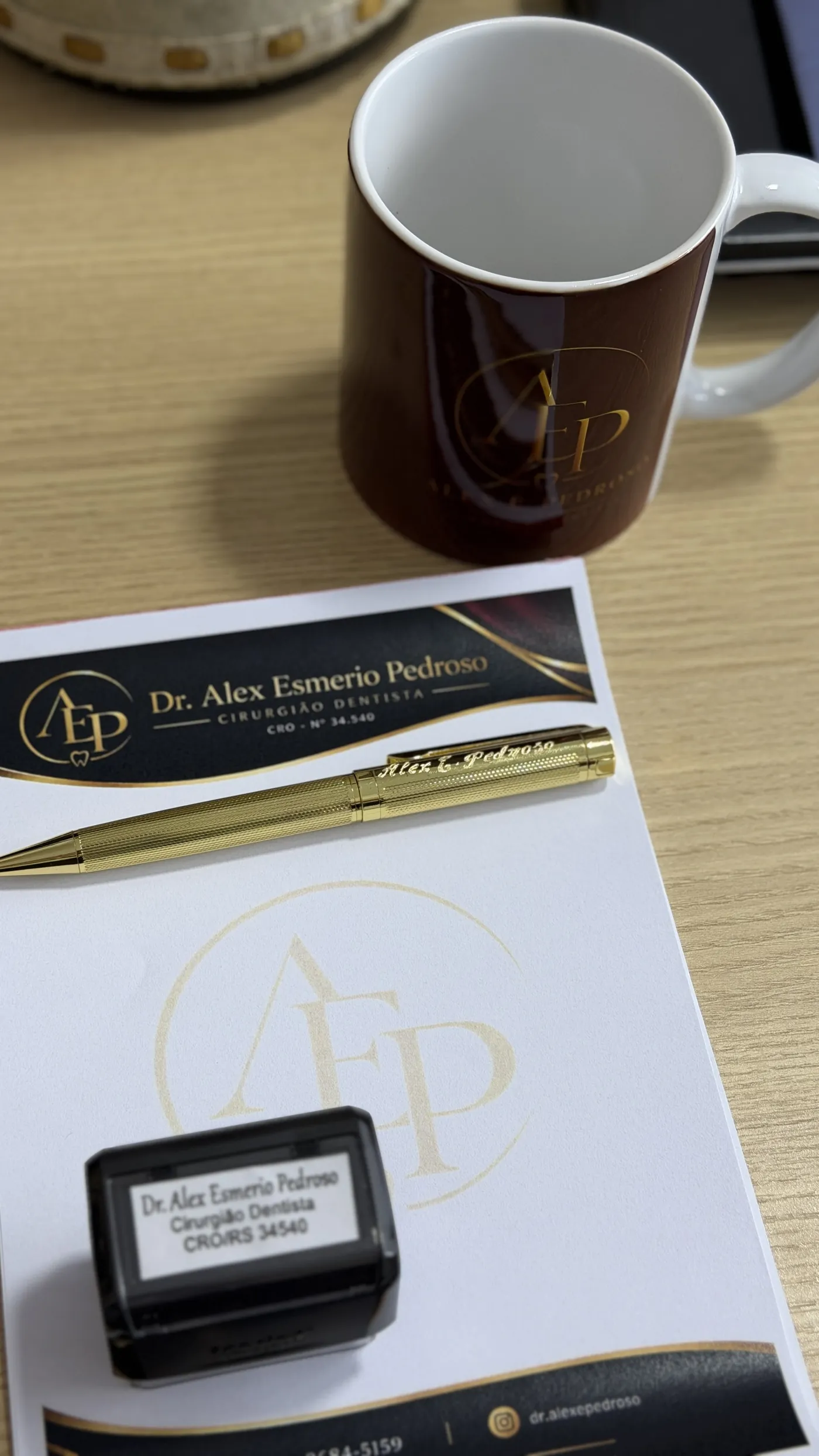 Papelaria do consultório com o monograma dourado AEP e caneta dourada